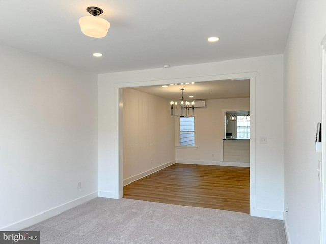 carpeted spare room featuring recessed lighting, baseboards, and an inviting chandelier