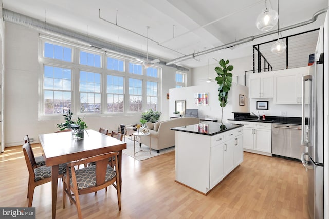 kitchen with light wood finished floors, appliances with stainless steel finishes, dark countertops, and white cabinetry