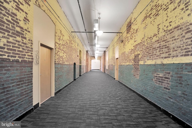 hall featuring carpet and brick wall