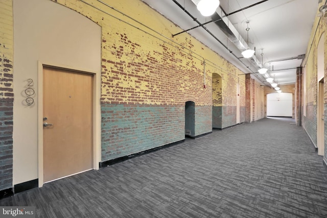 corridor featuring carpet floors and brick wall