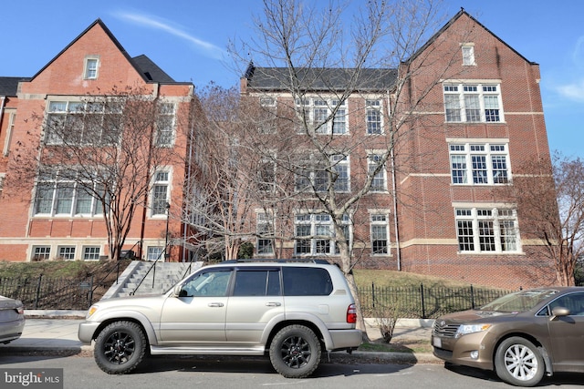 view of front facade with brick siding and fence