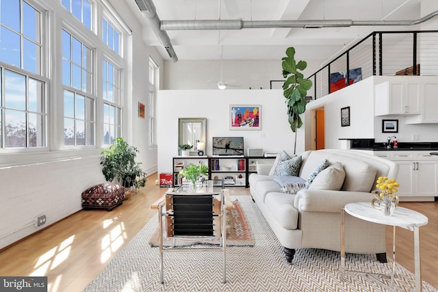 living room with light wood-style floors, a high ceiling, and visible vents