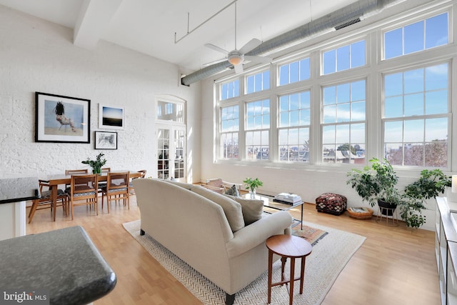 living room featuring beam ceiling, light wood-style flooring, and a healthy amount of sunlight