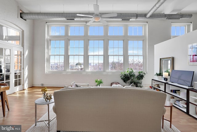 living area with visible vents, a ceiling fan, a towering ceiling, and light wood-style floors