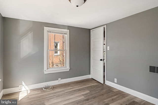 unfurnished room with visible vents, baseboards, and wood finished floors