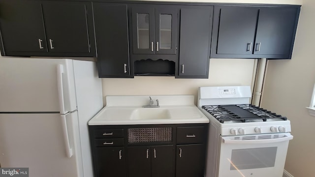 kitchen with white appliances, glass insert cabinets, light countertops, and dark cabinets