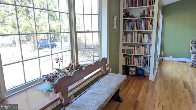 sitting room with visible vents, built in features, wood finished floors, and baseboards