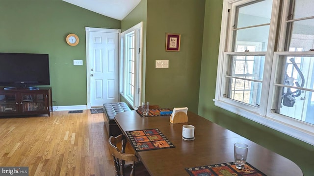 dining room with wood finished floors, baseboards, and vaulted ceiling