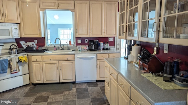 kitchen featuring white appliances, a sink, light countertops, stone finish floor, and glass insert cabinets