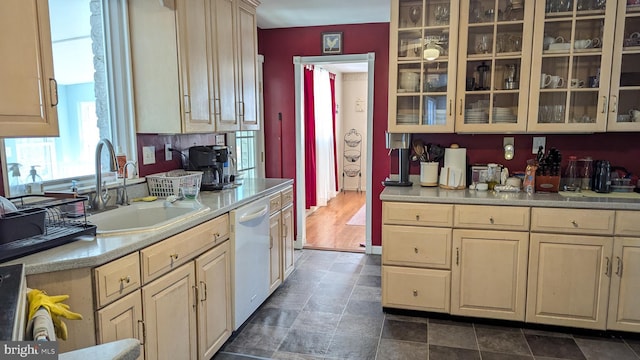 kitchen featuring a sink, glass insert cabinets, white dishwasher, and light countertops