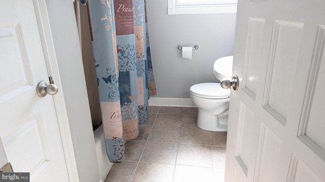 full bathroom featuring a shower with curtain, tile patterned floors, toilet, and baseboards