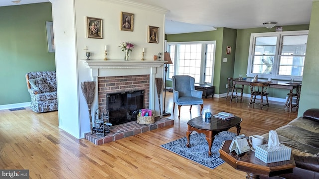 living area with baseboards, wood finished floors, and a fireplace