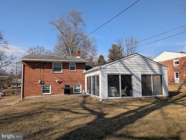 back of house with a yard, brick siding, and a sunroom