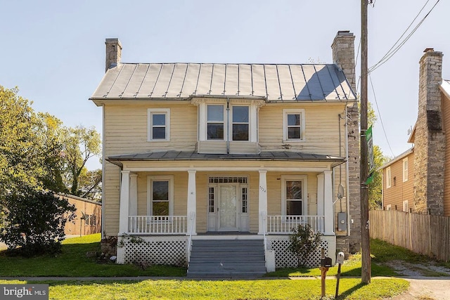 view of front of property featuring metal roof, a standing seam roof, a chimney, and a porch