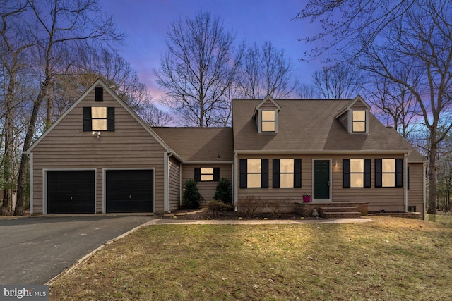 cape cod home featuring a yard, driveway, and a garage