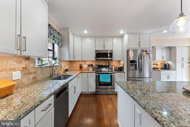 kitchen with a sink, white cabinetry, appliances with stainless steel finishes, decorative backsplash, and light stone countertops