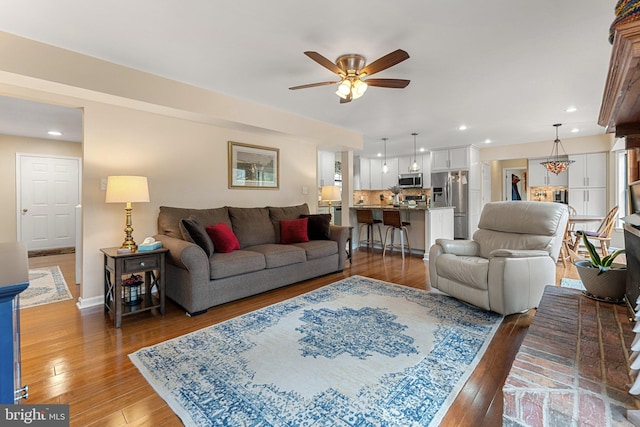 living area with recessed lighting, ceiling fan, light wood-style flooring, and baseboards