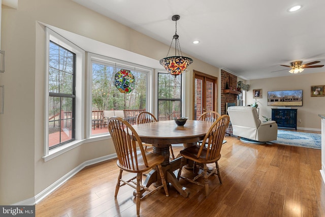 dining area with light wood-type flooring, a brick fireplace, baseboards, and recessed lighting