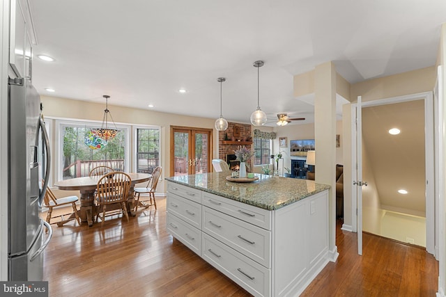 kitchen featuring a fireplace, wood finished floors, white cabinets, and stainless steel fridge with ice dispenser