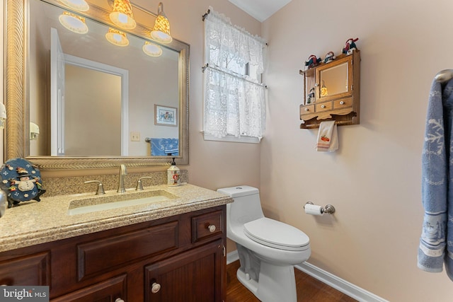 bathroom with toilet, baseboards, wood finished floors, and vanity