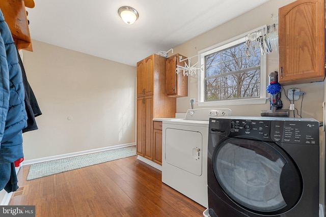 washroom featuring washer and clothes dryer, wood finished floors, cabinet space, and baseboards