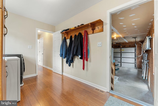 interior space featuring washer / dryer, laundry area, baseboards, visible vents, and wood finished floors