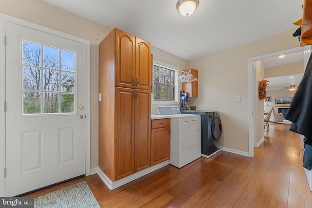 laundry area featuring dark wood-style flooring, washing machine and dryer, cabinet space, and baseboards