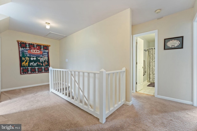 hall with attic access, baseboards, carpet flooring, and an upstairs landing