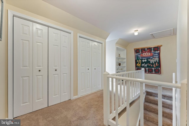 hallway with carpet, attic access, and built in features