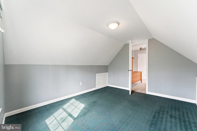 bonus room with lofted ceiling, dark colored carpet, and baseboards