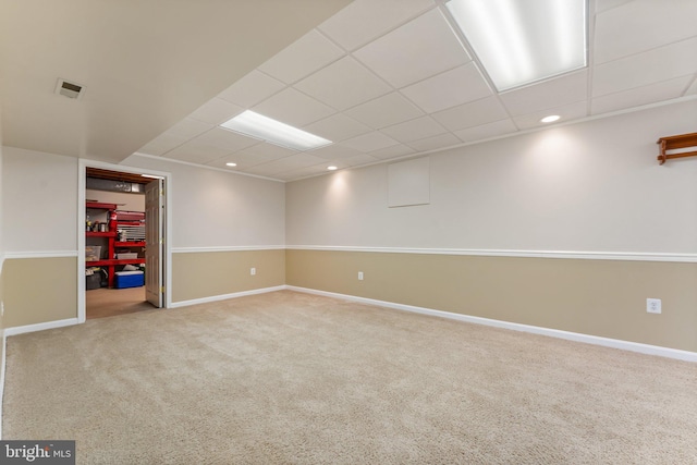 finished basement featuring carpet floors, a drop ceiling, visible vents, and baseboards