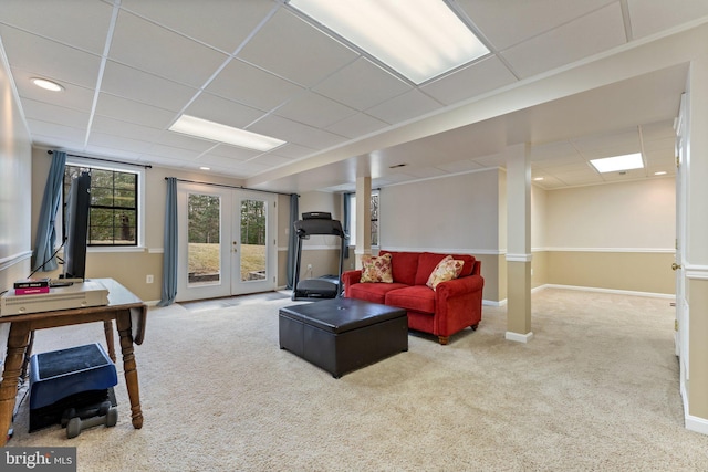 carpeted living area featuring baseboards, a drop ceiling, and french doors