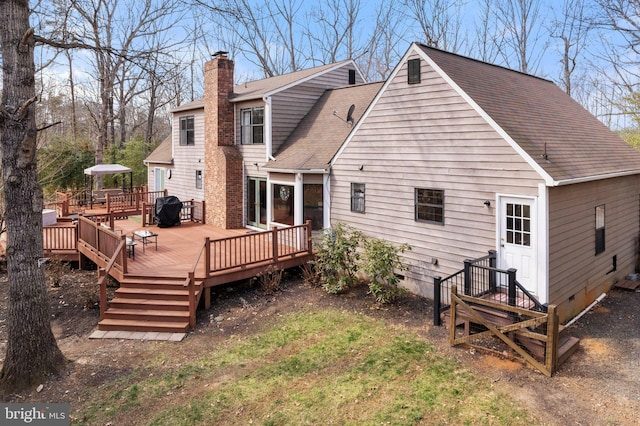 back of property featuring crawl space, a chimney, a deck, and roof with shingles