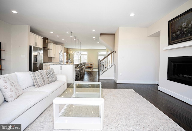 living room featuring baseboards, dark wood-style flooring, stairs, a fireplace, and recessed lighting