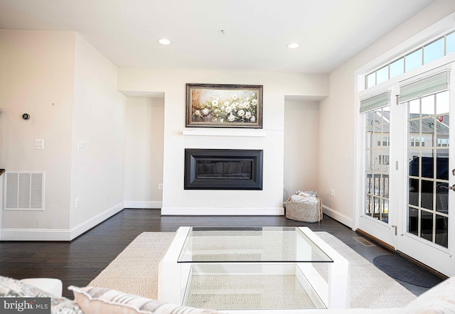 living area featuring baseboards, visible vents, a glass covered fireplace, dark wood-style floors, and recessed lighting