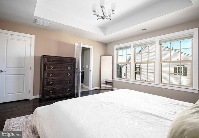 bedroom with a tray ceiling, visible vents, and baseboards