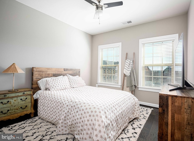 bedroom with ceiling fan, wood finished floors, visible vents, and baseboards