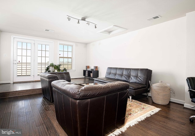 living area featuring attic access, visible vents, baseboards, and wood finished floors