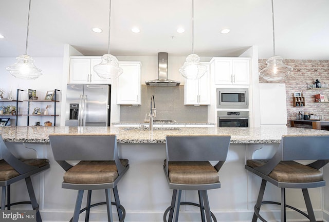 kitchen featuring wall chimney range hood, white cabinetry, appliances with stainless steel finishes, and tasteful backsplash