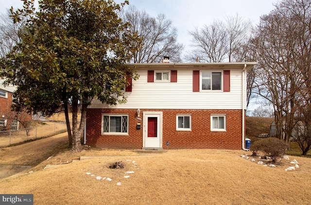 view of front of house featuring fence and brick siding