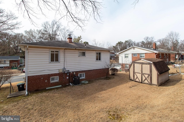 rear view of property featuring central air condition unit, a chimney, a storage shed, a yard, and an outdoor structure