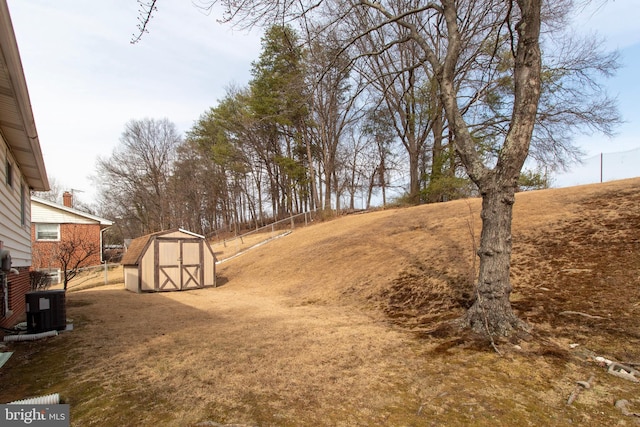 view of yard featuring fence, central AC, an outdoor structure, and a shed