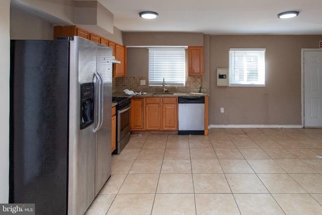 kitchen with tasteful backsplash, light tile patterned floors, light stone counters, stainless steel appliances, and a sink