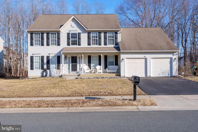 colonial inspired home with a garage, covered porch, aphalt driveway, and a front yard