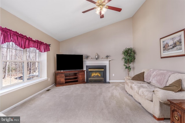 carpeted living area featuring vaulted ceiling, ceiling fan, a fireplace with flush hearth, and baseboards