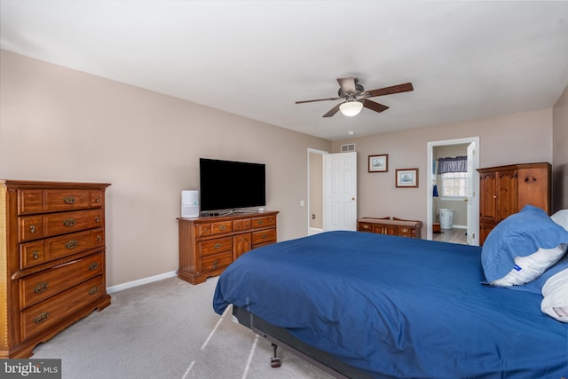 bedroom featuring baseboards, visible vents, a ceiling fan, light colored carpet, and ensuite bath