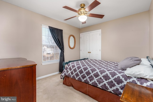 bedroom featuring light carpet, a closet, a ceiling fan, and baseboards