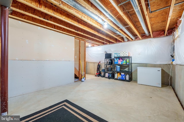 unfinished basement with fridge