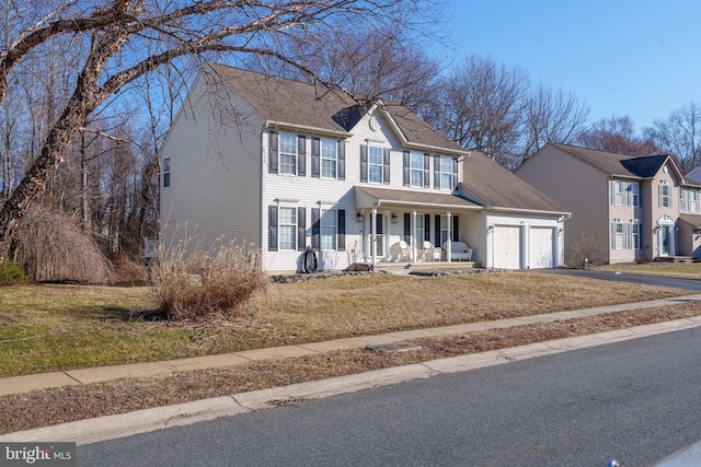 colonial home featuring aphalt driveway, a porch, a shingled roof, an attached garage, and a front lawn