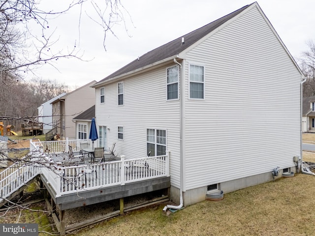 back of property with a deck and a yard